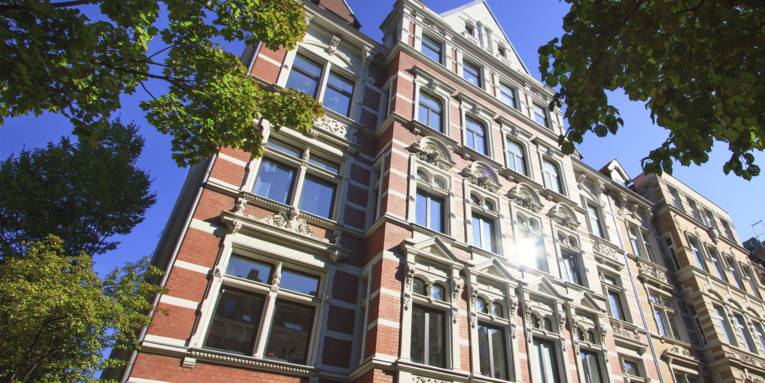 Viktorianisches Backstein Mehrfamilienhaus mit grünen Bäumen.